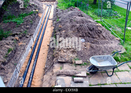 moderne Kunststofftechnik schwarz Heizungsrohre im Graben und gebrauchte barrow Stockfoto