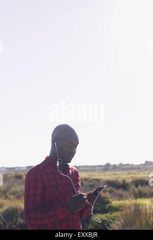Mann mit Smartphone und Kopfhörer im freien Stockfoto