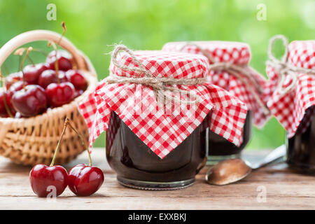 Gläser Marmelade und Korb mit Kirsche. Stockfoto