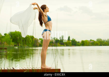 Frau im Bikini stehen am Ende der See Pier, mit Schal im Wind Stockfoto