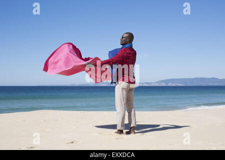 Mann am Strand, mit Decke im Wind Stockfoto