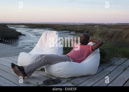 Mann entspannend auf Dock am Wasser Stockfoto