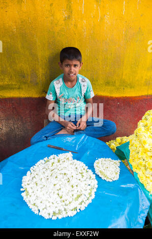 MUMBAI, Indien - 26. Oktober 2012: Indisches Kind hilft Zeichenfolge Blumenschmuck für die bevorstehende hinduistische Diwali-fest. Stockfoto