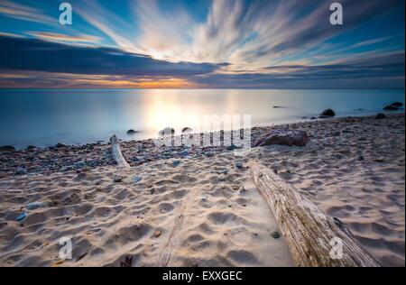 Beautifu felsigen Küste mit Treibholz Bäume Stämme bei Sonnenaufgang oder Sonnenuntergang. Ostsee-Küste Stockfoto