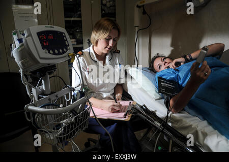 Ein Patient wird von einer Krankenschwester in eine Krankenstation untersucht.     Bildnachweis: Euan Cherry Stockfoto