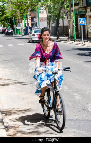 Junge Frau mit dem Fahrrad in Tracht Sevilla in Sevilla, Sevilla, Andalusien, Spanien, Europa-Center. Während der April Feria Stockfoto