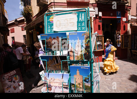 Postkarten für Verkauf und Frau im traditionellen Sevilla dress in den engen Gassen der Altstadt, Santa Cruz, beliebt bei Touristen Stockfoto