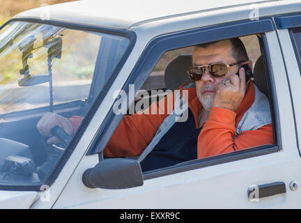 Porträt eines alten Mannes sitzen in einem alten Auto und Anruf Stockfoto