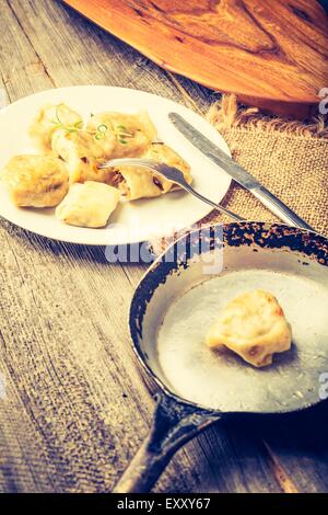 Vintage Foto von frittierten Teigtaschen mit Zwiebel in einer Pfanne erhitzen. Stockfoto