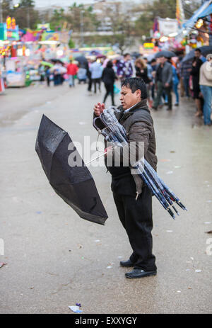 Regenschirm Verkäufer an einem nassen Regentag in Sevilla, Andalusien, Spanien, Europa. Auf April Feria Festival. Stockfoto