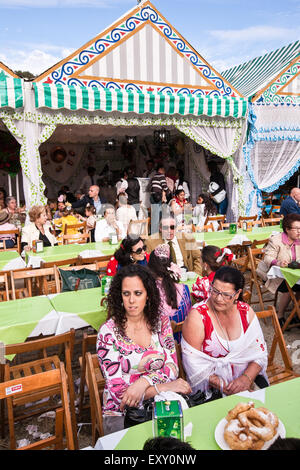 Einheimische in traditionellen Sevilla Kleid mit Snacks von Donuts und Schokoladengetränke Chocolat con Churros in Sevilla, Andalusien, Stockfoto