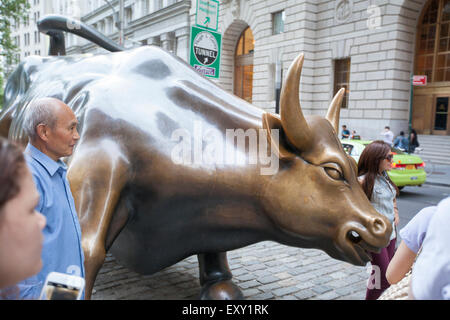 NEW YORK - 28. Mai 2015: Touristen posieren für Bilder mit dem Aufladen Stier, die manchmal auch als die Wall Street Stockfoto