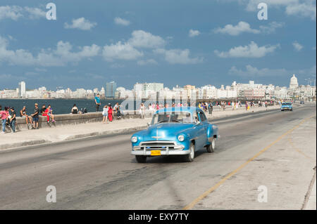 Havanna, Kuba - 18. Mai 2011: Klassisch blau American Taxi fährt neben Massen der Kubaner entspannend auf dem Malecon in Vedado. Stockfoto