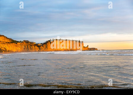 Goldenes Licht fällt auf den Klippen in der Nähe der Stadt am Strand von Montanita, Ecuador Stockfoto