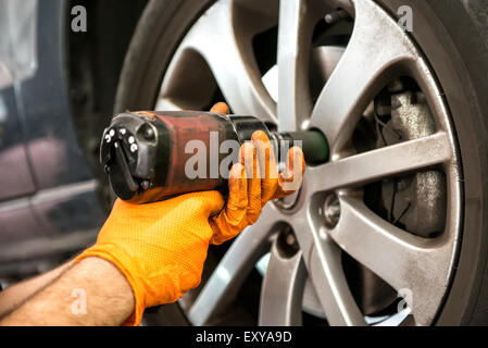 Mechaniker arbeiten auf einem Auto-Rad festziehen oder lösen von Schrauben an der Nabe und Felge mit einem Elektrowerkzeug, Nahaufnahme Stockfoto