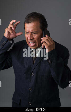 Hispanic Geschäftsmann reden auf seinem Handy, wütend und frustriert. Stockfoto