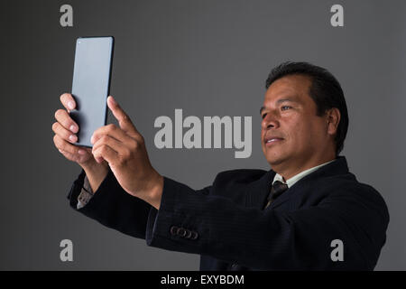 Ein Hispanic Geschäftsmann hält ein Mini-Ipad oder Tablet, wobei ein Selbstporträt. Stockfoto