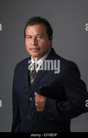 Ein Hispanic Geschäftsmann hält ein Mini-Ipad oder Tablet, posiert für ein Business-Portrait. Stockfoto