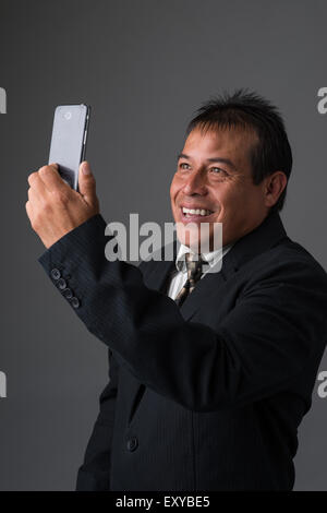 Hispanic Geschäftsmann halten, wobei ein Selbstporträt mit seinem Handy. Stockfoto
