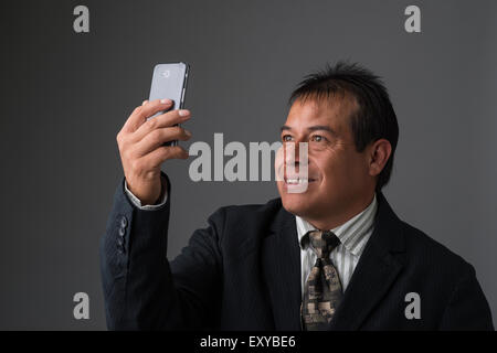 Hispanic Geschäftsmann halten, wobei ein Selbstporträt mit seinem Handy. Stockfoto