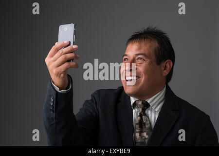 Hispanic Geschäftsmann halten, wobei ein Selbstporträt mit seinem Handy. Stockfoto