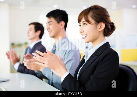 Business-Leute sitzen in einer Reihe und applaudieren Stockfoto