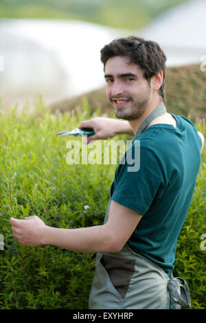 Blick auf eine junge attraktive Gärtner schneiden Blätter Stockfoto