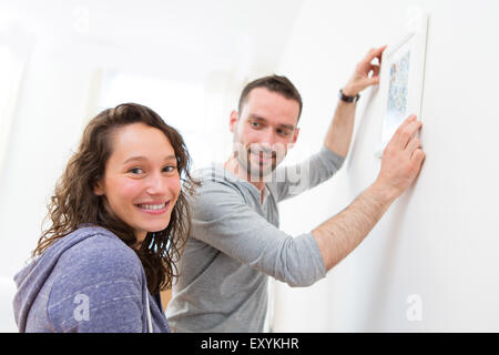 Blick auf ein paar hängt ein Gemälde in ihrer neuen Wohnung Stockfoto
