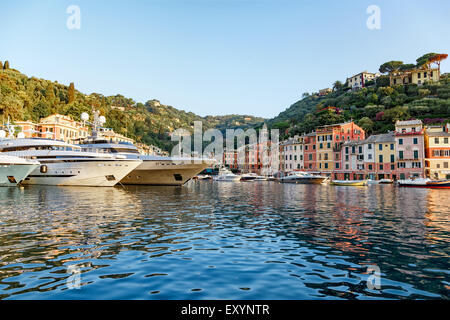 Malerische Aussicht auf große Luxusjachten vertäut im Hafen vor dem bunten Fischen Dorf von Portofino, Ligurien, Ita Stockfoto