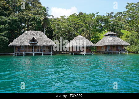 Tropische Küste mit strohgedeckten Bungalows über dem Wasser an der karibischen Küste von Panama, Bocas del Toro, Mittelamerika Stockfoto