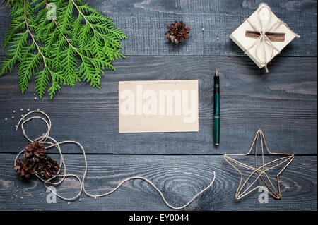 Geschenk, Postkarte, Tannenzapfen, Thuja und Zimt auf den dunklen Holztisch strukturierte Stockfoto