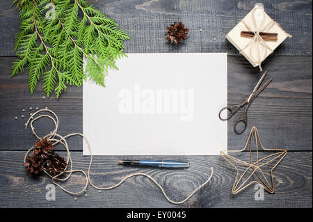 Geschenk, Postkarte, Tannenzapfen, Thuja und Zimt auf den dunklen Holztisch strukturierte Stockfoto