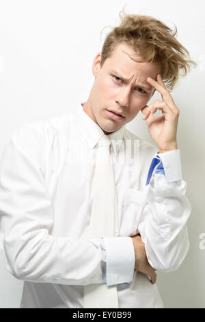 Ein hübscher junger Mann, männliches Model trägt ein weißes Hemd mit weißen Krawatte, posiert mit strubbeligem Haar. Stockfoto