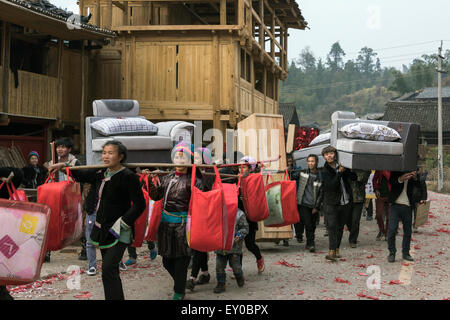 Junge Männer tragen die Möbel Hochzeitsgeschenke, Huanggang Dong Dorf, Guizhou Provinz, China Stockfoto