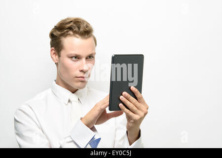 Ein hübscher junger Mann mit einem Ipad/Tablet. Er trägt eine schneeweiße Outfit, eine saubere futuristisches Konzept. Stockfoto