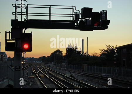 Eine rote Stoppsignal neben Bahnlinien Richtung Westen bei Sonnenuntergang.  Bahnhof Basingstoke, Hampshire, UK. Stockfoto