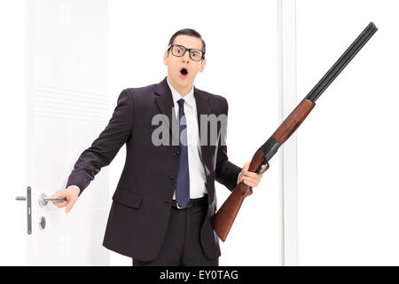 Mann mit Gewehr stehend durch eine Tür isoliert auf weißem Hintergrund Stockfoto