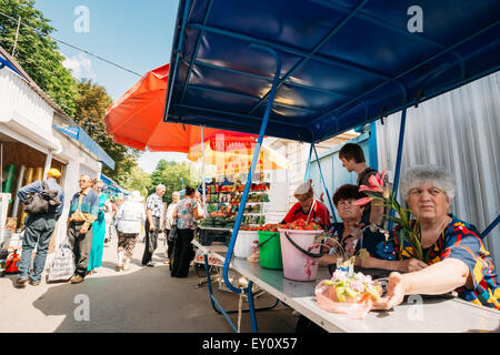 GOMEL, Weißrussland - 10. Juni 2014: Eine unbekannte Frau verkauft Gemüsesamen, Erdbeeren und Blumen auf dem lokalen Markt Stockfoto