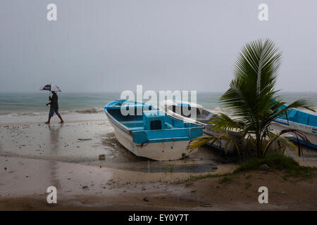 Lokale Mann zu Fuß unter dem Regen auf ein tropischer Sturm auf Corn Island, Nicaragua Stockfoto