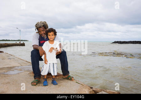 Nicaraguanische Vater und Sohn auf der Suche und lächelt in die Kamera bei Big Corn Island dock, Nicaragua Stockfoto