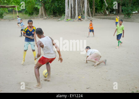 Kolumbianische Jungs spielen Fußball (Fußball) unter einem Banyanbaum durch das Dorf Fluss. Stockfoto