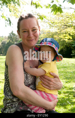 Mutter, kuscheln ihr Babymädchen in den Garten an einem schönen Sommertag Stockfoto