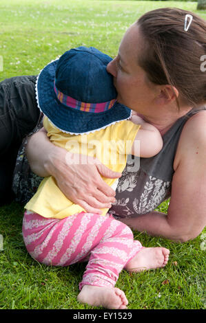 Mutter tröstet ihr kleines Mädchen in den Garten Stockfoto
