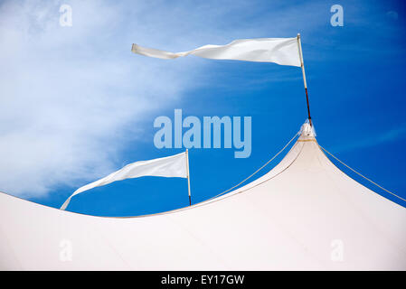 Zelt-Dach mit weißen Fahnen im Wind vor blauem Himmel Stockfoto