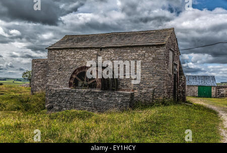 Stein-Bergbau-Hütte und rostigen alten Winde auf einer verlassenen führen mir im Peak District in Derbyshire mit dramatischen Wolkenhimmel Stockfoto