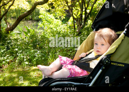 Babymädchen in ihrem Kinderwagen im Freien suchen besorgt Stockfoto
