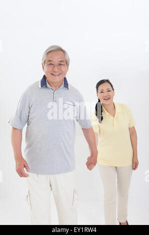 Älteres Paar Hand in Hand und lächelt in die Kamera zusammen, Stockfoto