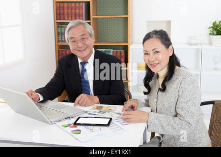 Älteres paar Geldanlage diskutieren und lächelt in die Kamera zusammen, Stockfoto