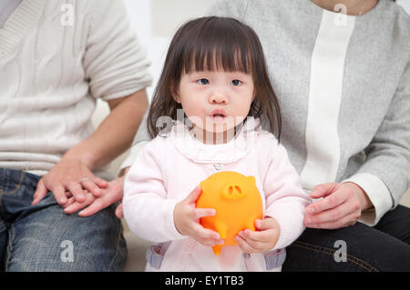 Familie mit einem Kind mit Sparschwein Stockfoto