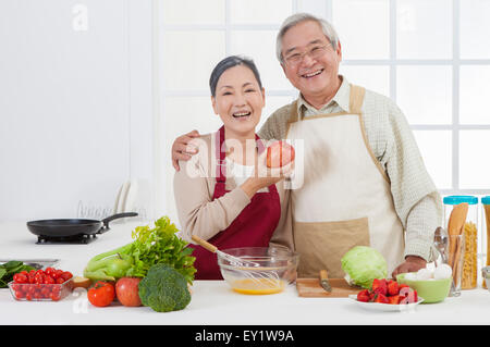 Älteres paar Gemüse in der Küche und lächelt in die Kamera halten, Stockfoto